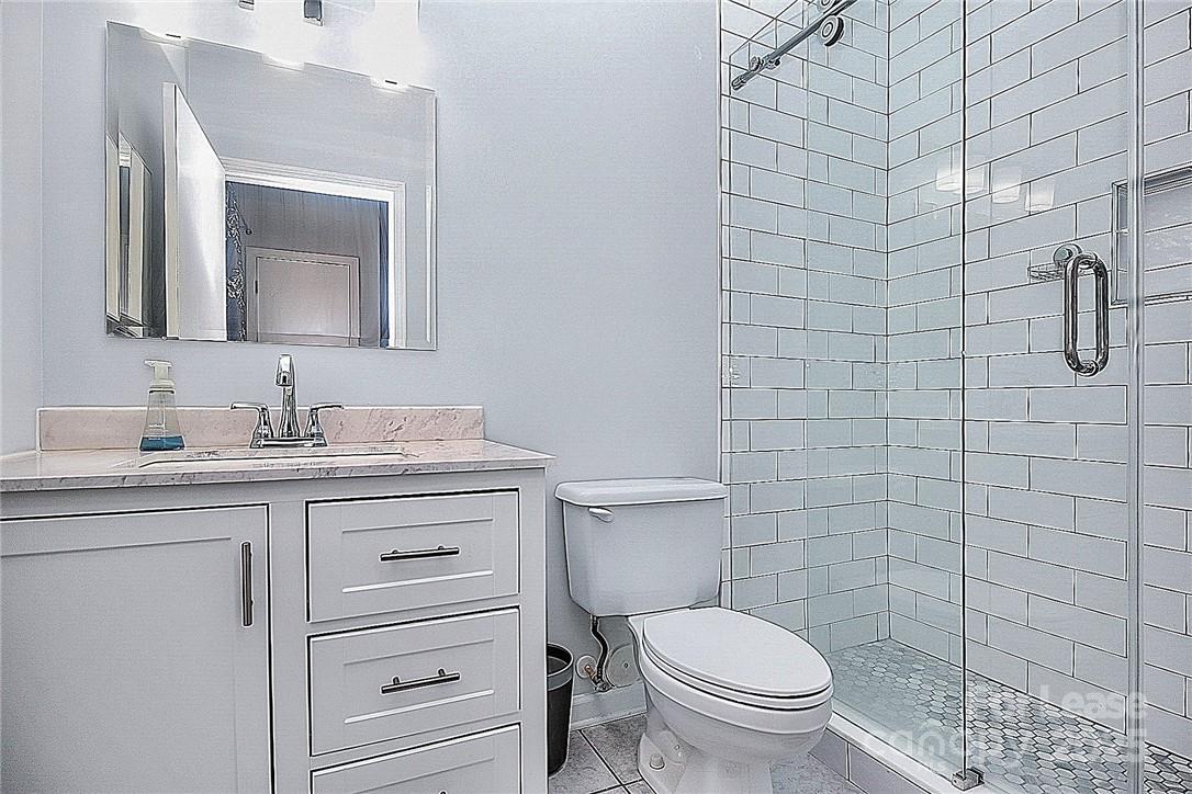 2625 East 5th Street, Unit A Charlotte, NC 28204 - Photo 24 of 24 a bathroom with a granite countertop toilet sink and mirror