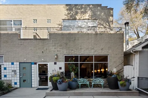 a front view of a house with glass windows and potted plants