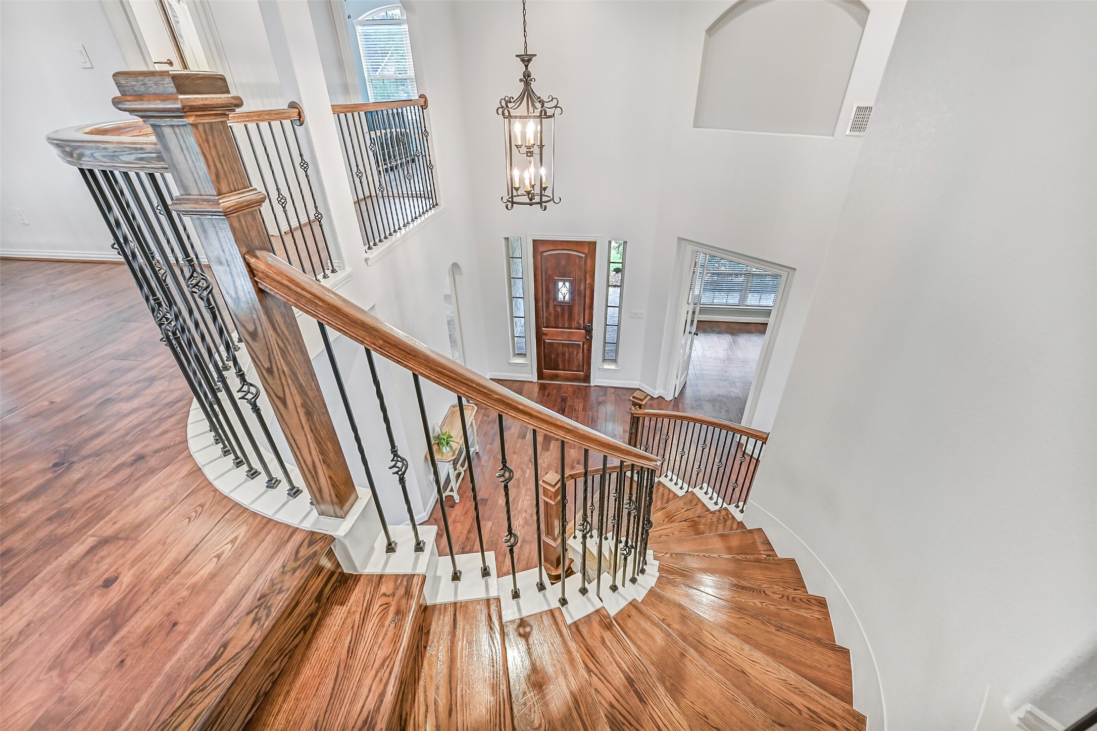 1008 Point Isabel Lane Friendswood, TX 77546 - Photo 34 of 50 An elegant overlook from the second floor highlights the sweeping staircase with wood treads, iron balusters, and a dramatic two story entry anchored by a statement chandelier and natural light from surrounding windows.