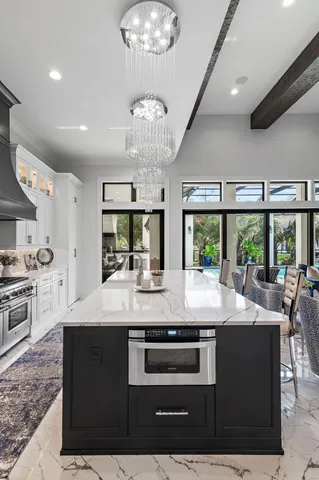 a room with kitchen island granite countertop a sink stainless steel appliances and a large window
