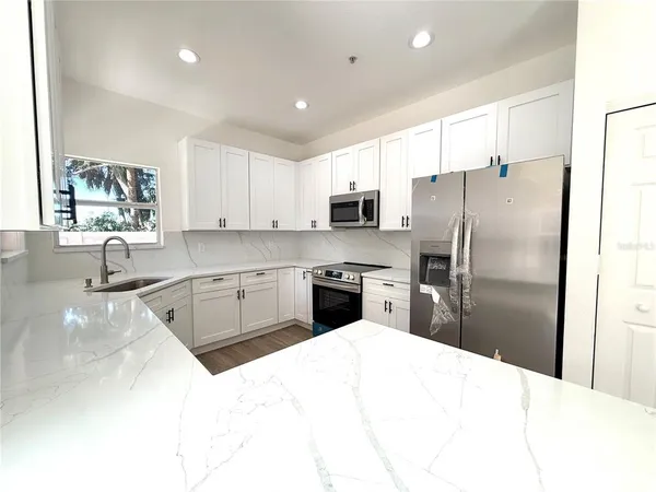 a kitchen with stainless steel appliances kitchen island granite countertop a refrigerator sink and cabinets