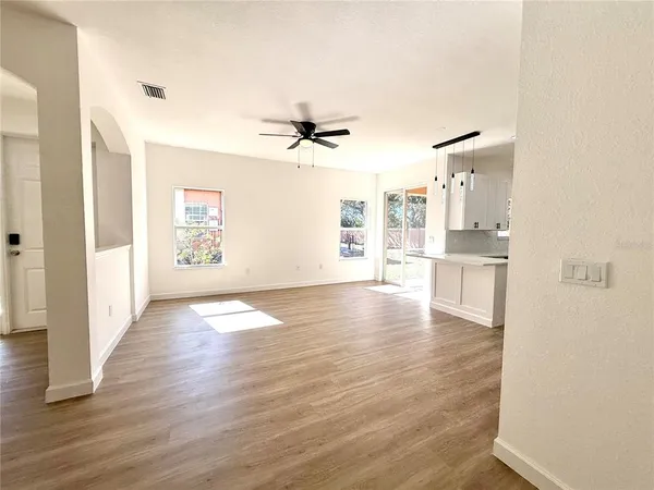 an empty room with wooden floor and a kitchen