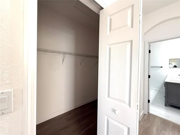 an empty room with wooden floor chandelier fan and windows