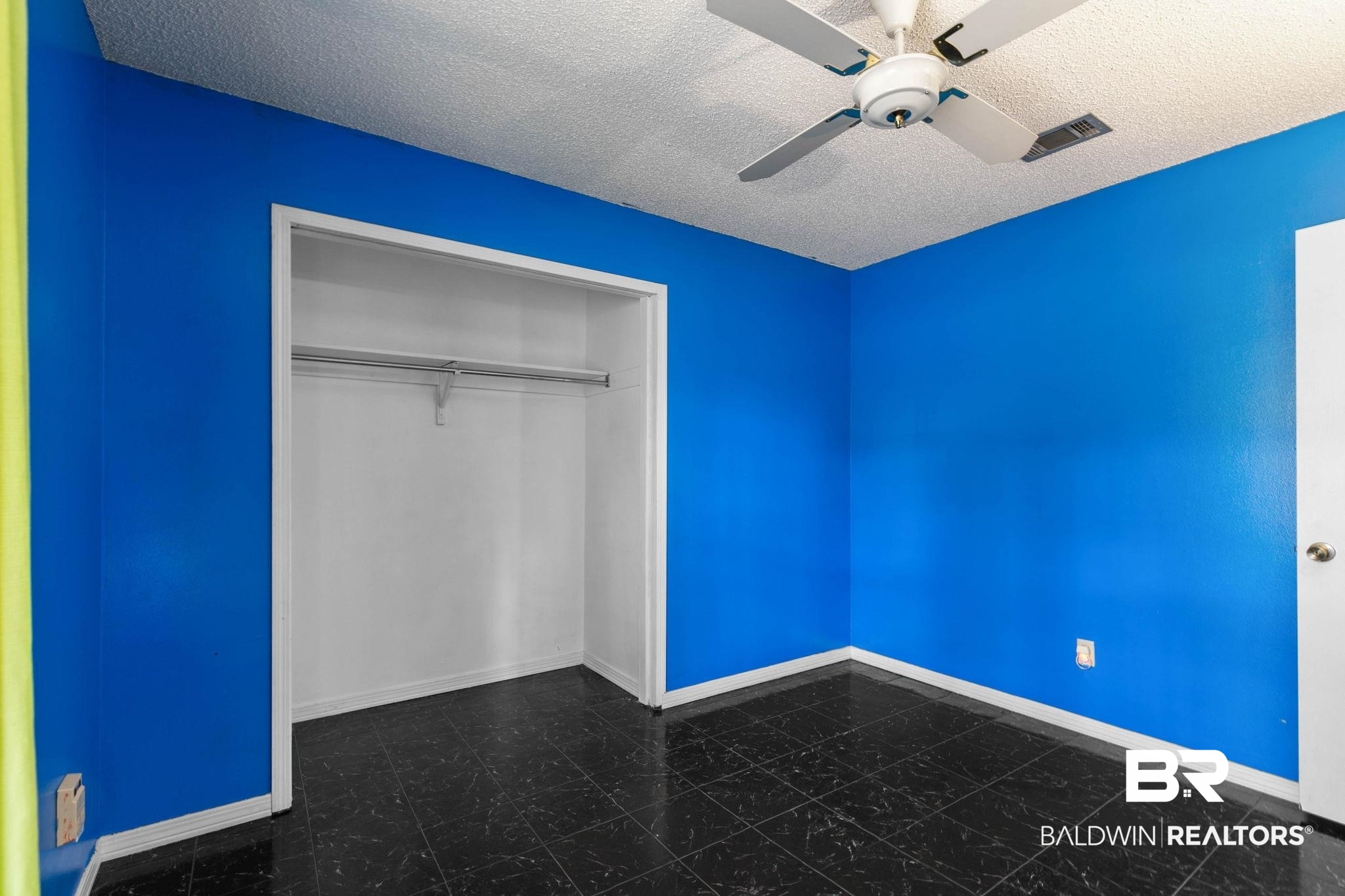 13653 Roberts Road Loxley, AL 36551 - Photo 22 of 33 Room featuring dark tile flooring, bright blue walls, and a white ceiling with a mounted ceiling fan