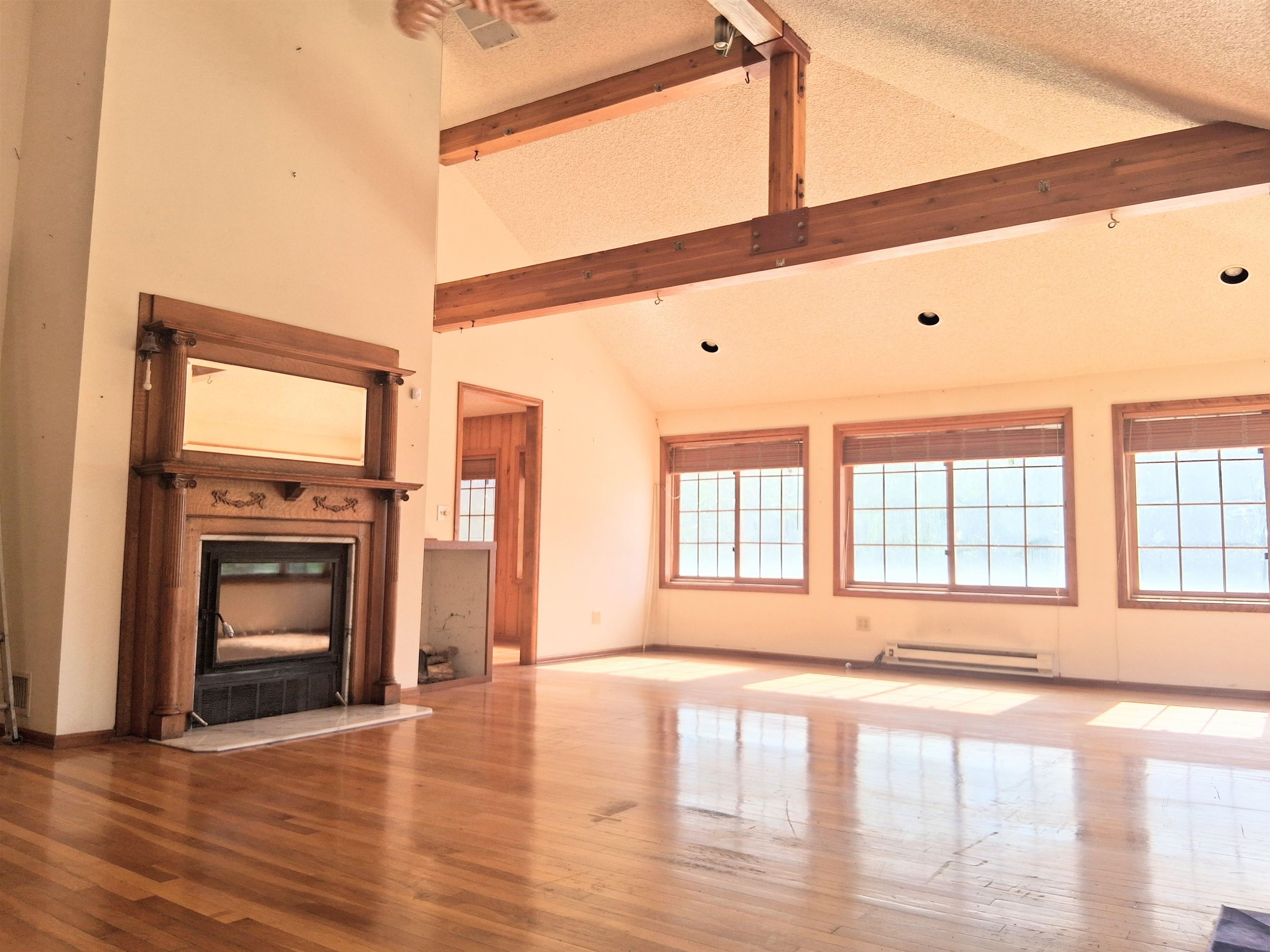 1983 River Road Fruita, CO 81521 - Photo 15 of 31 a view of an empty room with a fireplace and wooden floor next to windows