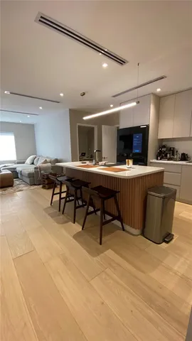 a large kitchen with a large counter top space a sink stainless steel appliances and cabinets