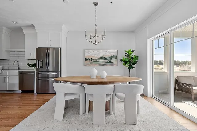 a dining room with stainless steel appliances a table chairs and kitchen view