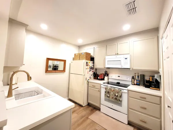 a kitchen with a refrigerator sink and white cabinets