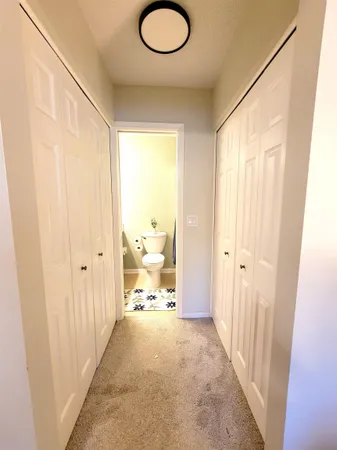 a view of a hallway to a livingroom with wooden floor and windows