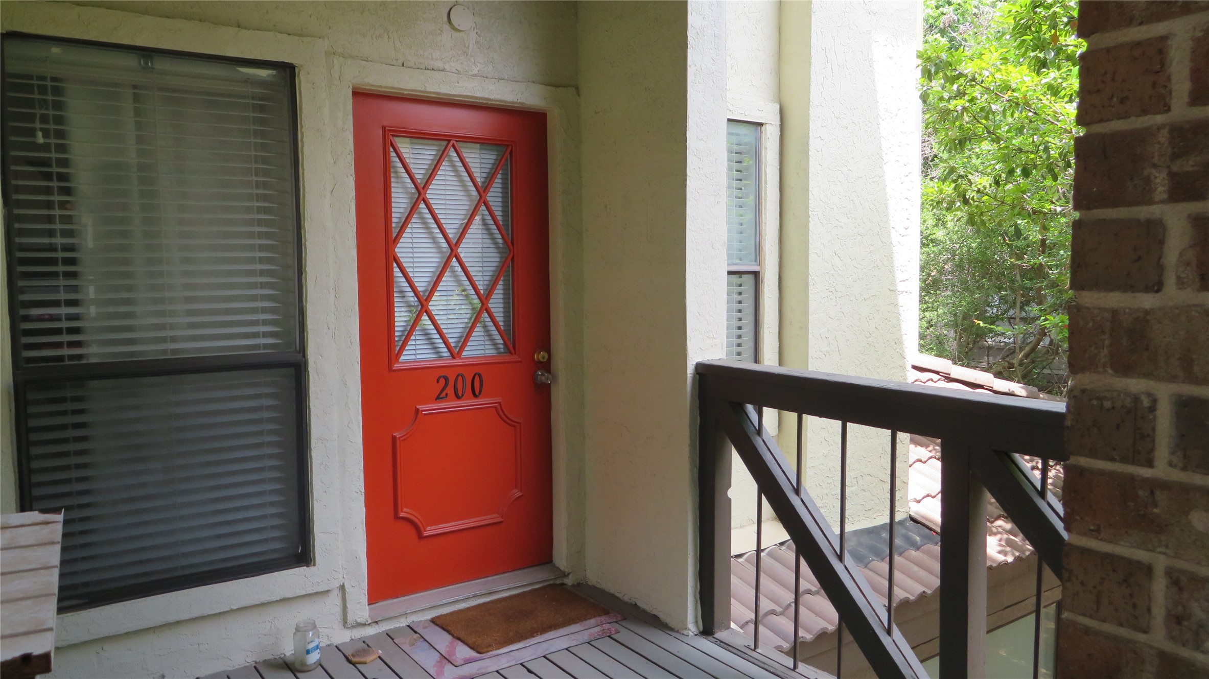 806 West 24th Street, Unit 200 Austin, TX 78705 - Photo 9 of 33 A vibrant orange entry door welcomes you to this inviting outdoor space, complete with a classic wooden railing.