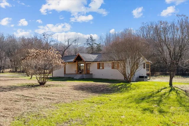 a view of a white house with a big yard and large trees