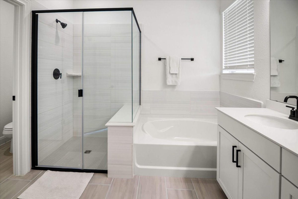 104 Raleigh Drive Georgetown, TX 78633 - Photo 23 of 37 Modern bath features a pristine shower with sleek black framing and a deep, inviting soaking tub.