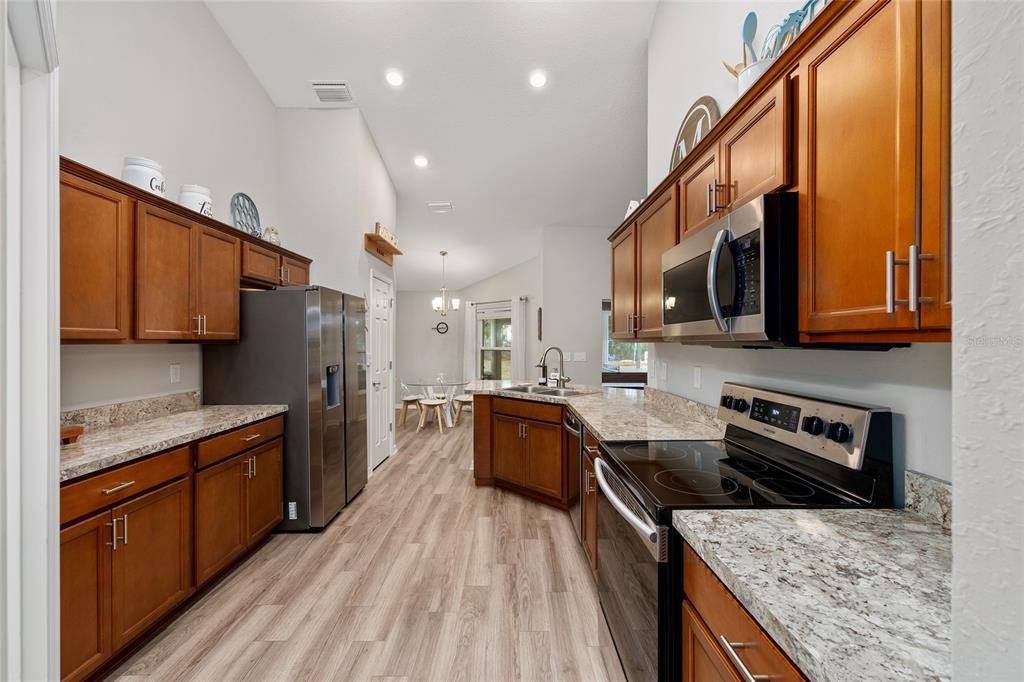 11275 Southwest 54th Circle Ocala, FL 34476 - Photo 24 of 63 a kitchen with stainless steel appliances granite countertop wooden cabinets a stove top oven a sink and dishwasher