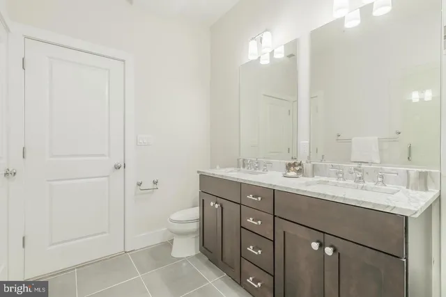 a bathroom with a double vanity sink mirror and toilet