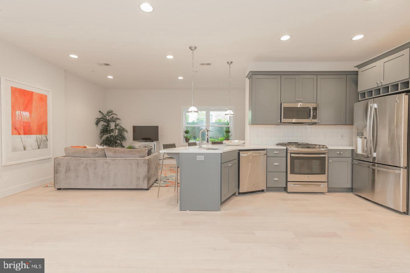 1352 Quincy Street Northwest, Unit 1 Washington, DC 20011 - Photo 7 of 26 a large kitchen with stainless steel appliances a large counter top a stove a microwave a sink and a refrigerator