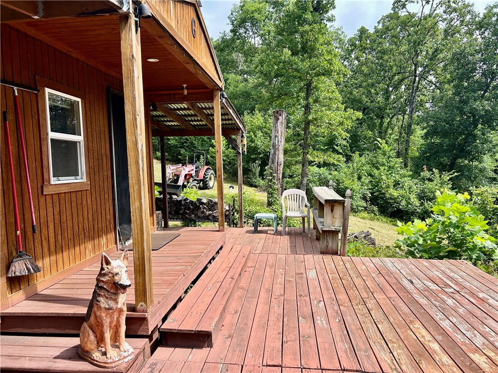 462789 East 820 Road Stilwell, OK 74960 - Photo 3 of 48 Expansive wood deck with direct access to a covered porch, featuring wood siding and a surrounding natural landscape