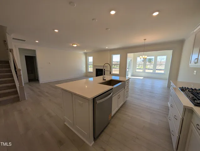 a large kitchen with stainless steel appliances a large counter top a stove a sink a refrigerator and a refrigerator