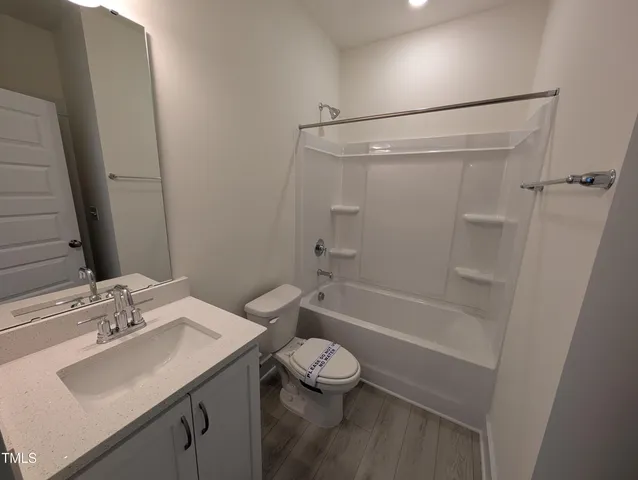 an empty room with wooden floor and a ceiling fan