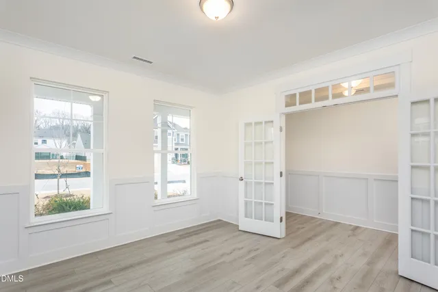 an empty room with wooden floor cabinet and windows