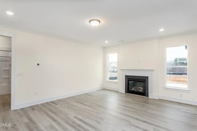 an empty room with wooden floor a fireplace and window
