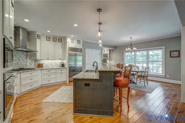 a view of a kitchen with kitchen island granite countertop a stove a sink a dining table and chairs