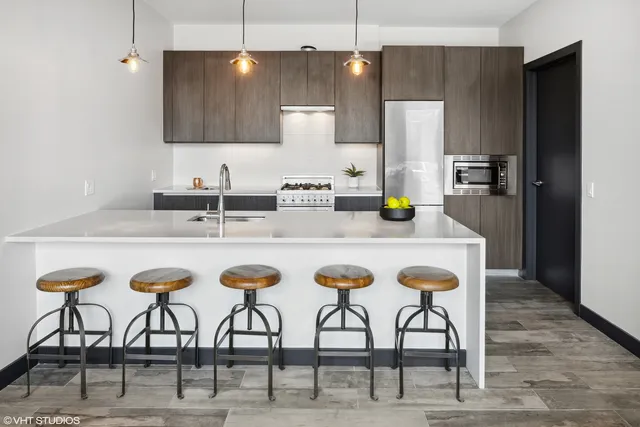 a kitchen with stainless steel appliances kitchen island granite countertop a dining table chairs and sink