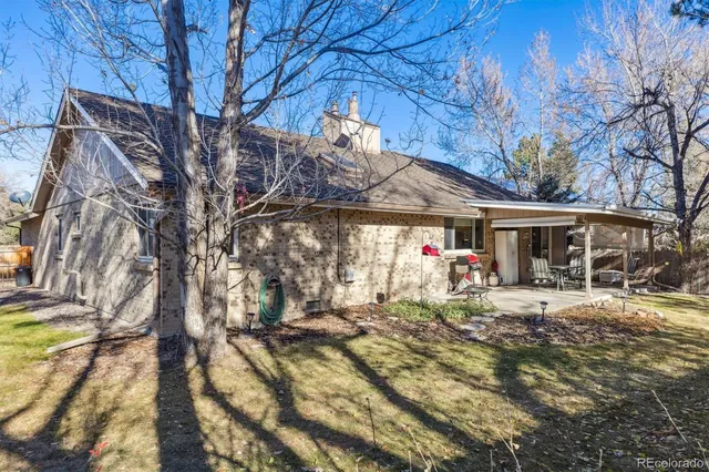 a front view of a house with a yard outdoor seating and covered with trees