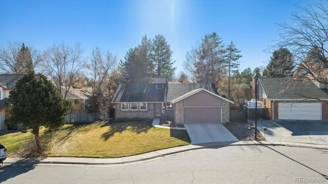 a view of a house with a small yard and large trees