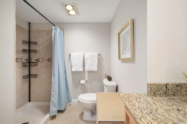 a bathroom with a granite countertop sink toilet and shower
