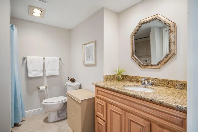 a bathroom with a granite countertop toilet sink and mirror