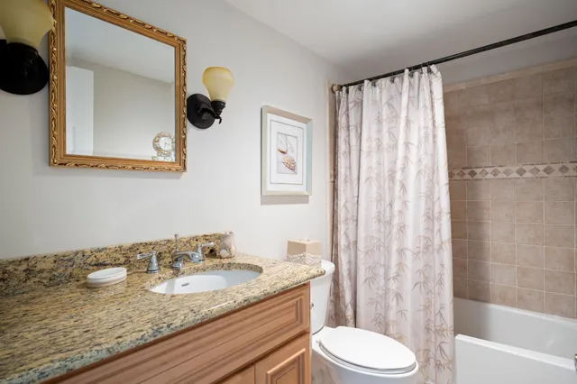 a bathroom with a granite countertop sink toilet and shower