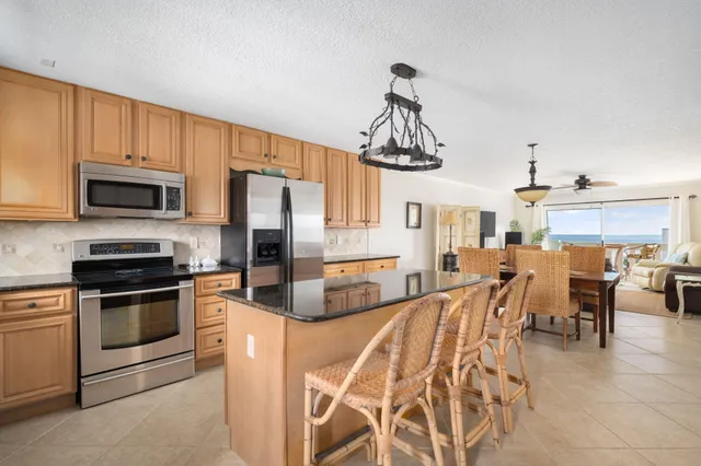 a kitchen with stainless steel appliances a stove a sink dishwasher a oven with a dining table and chairs