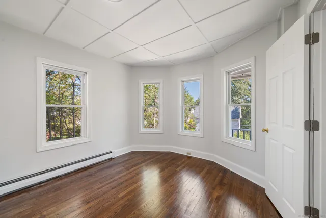 a view of empty room with wooden floor and fan