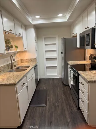 a kitchen with granite countertop white cabinets and a sink