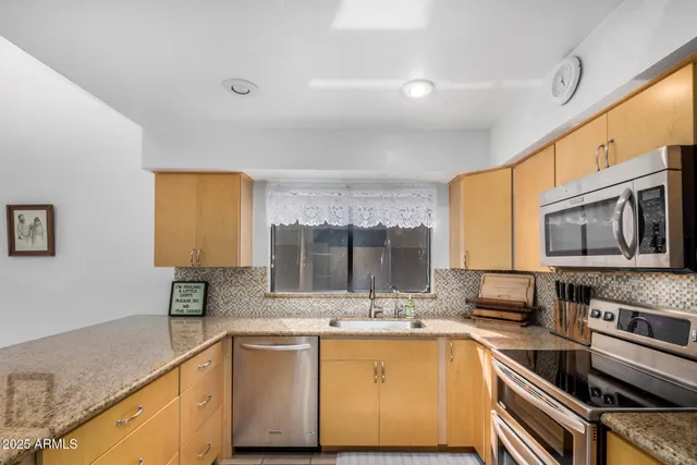 a kitchen with stainless steel appliances granite countertop a sink stove and microwave