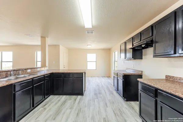 a large kitchen with granite countertop a stove top oven a sink dishwasher a dining table and chairs with wooden floor