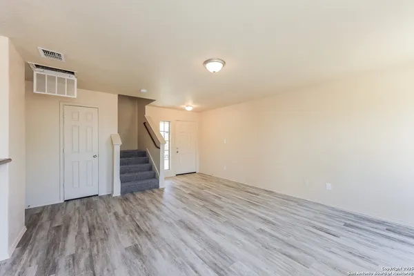 a view of an empty room with wooden floor and stairs