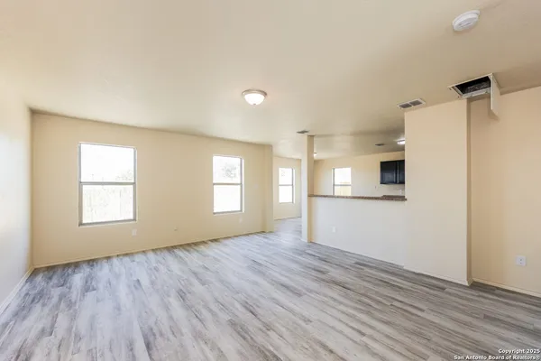 an empty room with wooden floor and windows