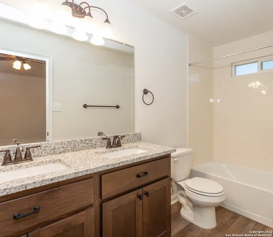a bathroom with a granite countertop sink toilet a large mirror a vanity and shower