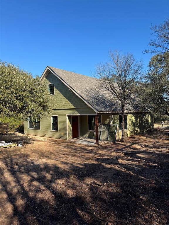 a backyard of a house with table and chairs under an umbrella