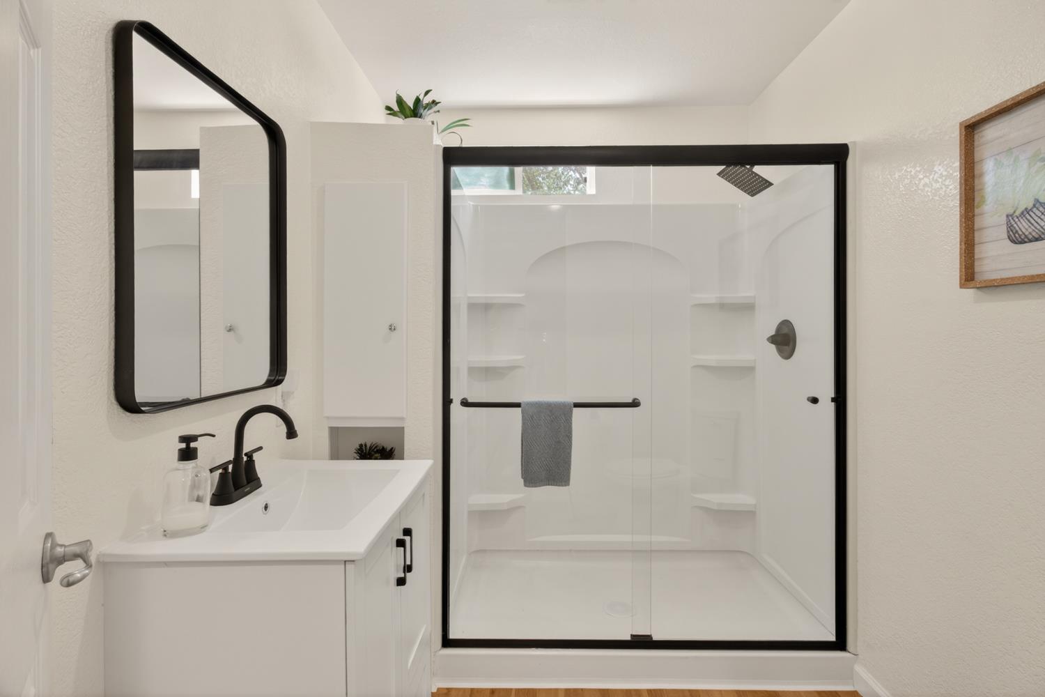 6332 Horseshoe Bar Road Loomis, CA 95650 - Photo 21 of 85 Bathroom featuring a white vanity with integrated sink, black fixtures, and a framed mirror
