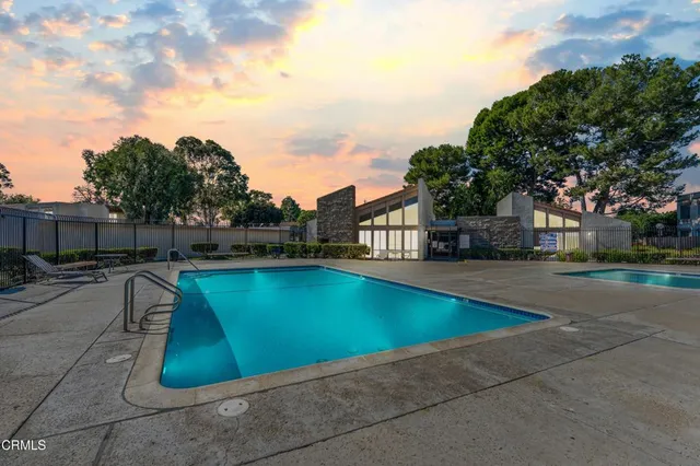 a view of swimming pool with seating space and trees in the background