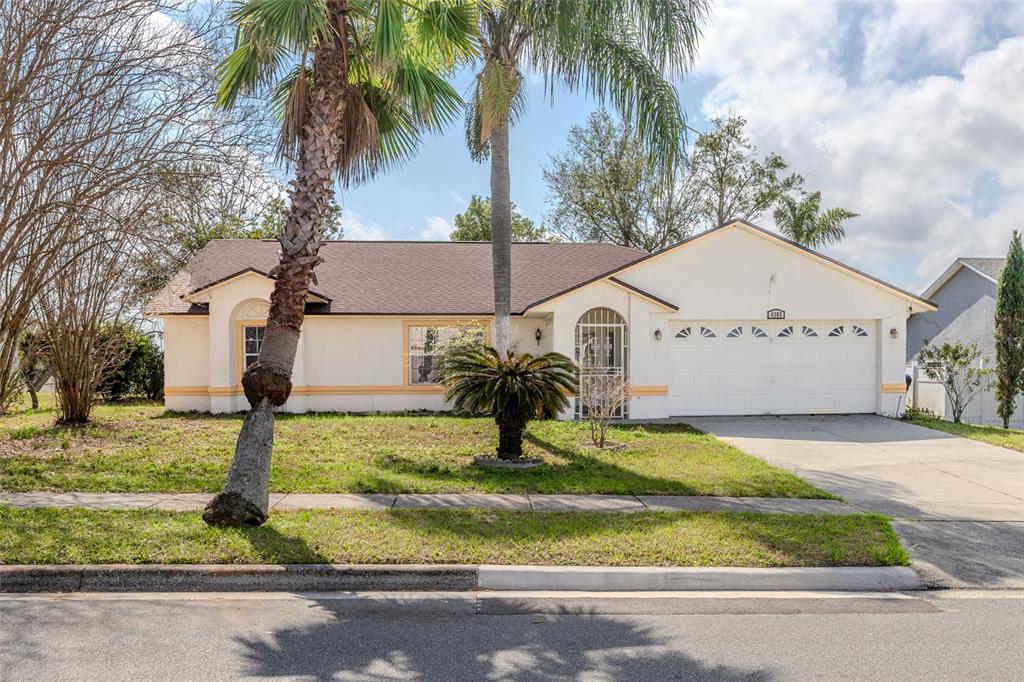 6385 Royal Tern Street Orlando, FL 32810 - Photo 1 of 1 a house with trees in the background next to a yard