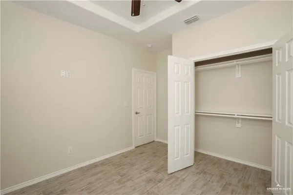 an empty room with kitchen view and wooden floor