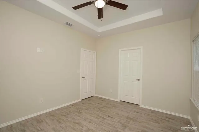 a view of an empty room and window and chandelier fan