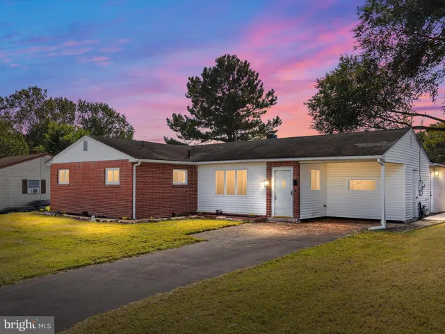 a front view of a house with yard and large trees