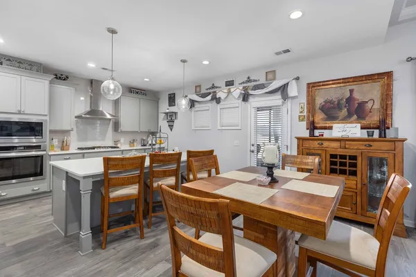 a kitchen with stainless steel appliances granite countertop a stove a sink dishwasher a dining table and chairs with wooden floor