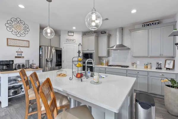 a kitchen with stainless steel appliances granite countertop a sink a stove a dining table and chairs