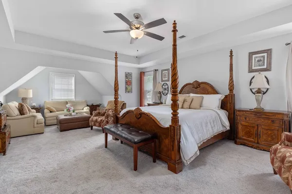 a spacious bedroom with a bed a couch and a chandelier