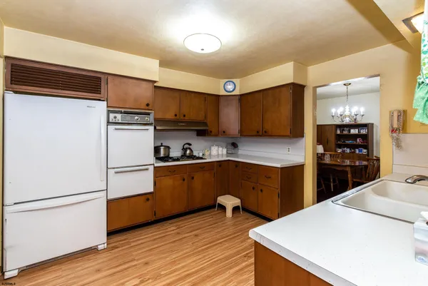 a kitchen with a refrigerator a stove top oven a sink and cabinets with wooden floor